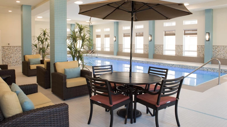 Lounge chairs and a table next to an indoor pool at Sage Hill retirement home